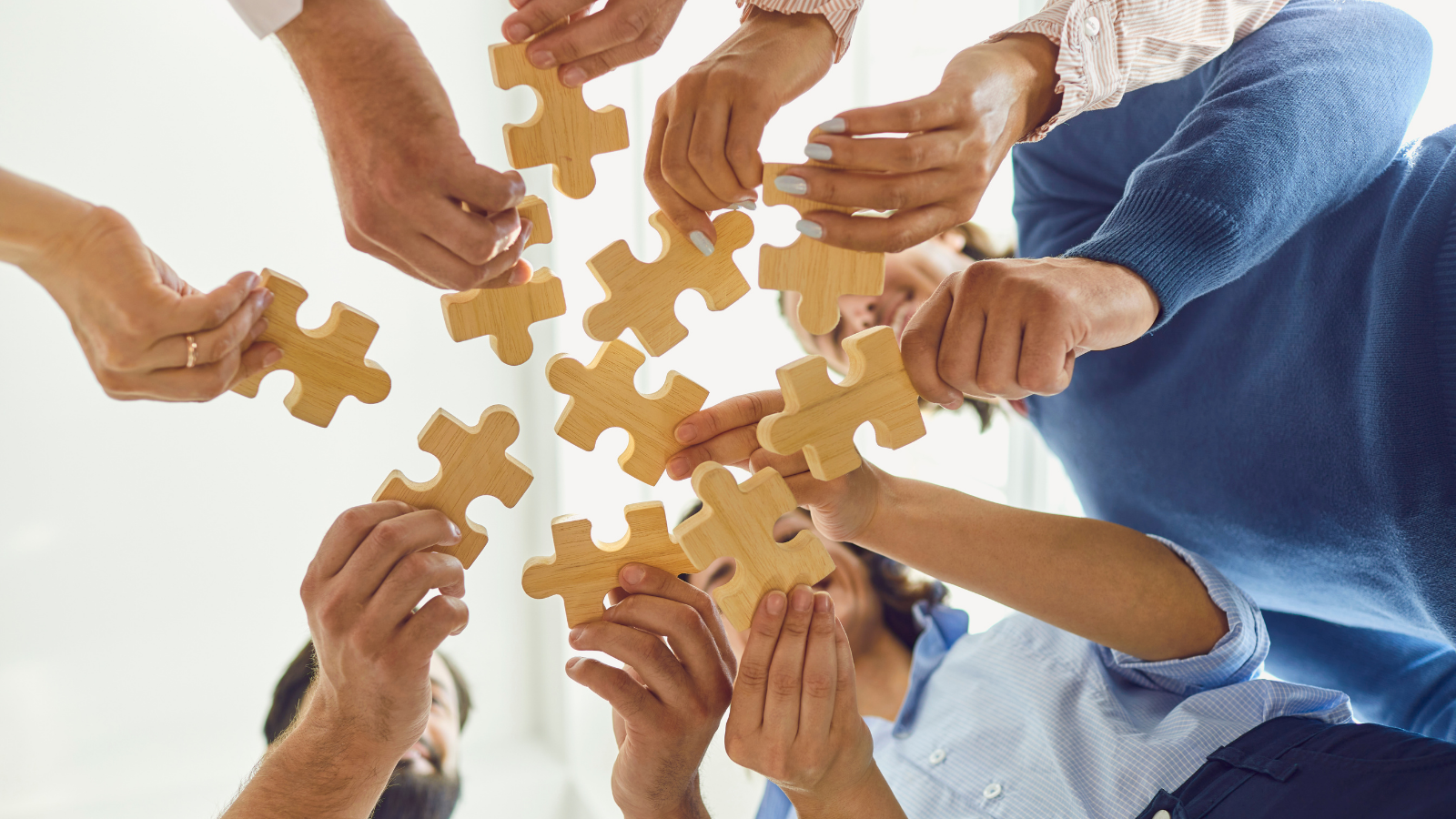 Pessoas unindo peças de quebra-cabeça, simbolizando colaboração, trabalho em equipe e integração de diferentes ideias e habilidades